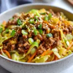 To make a tasty Low Carb Egg Roll in a Bowl, you need these ingredients: - 1 pound ground chicken or turkey - 4 cups coleslaw mix (shredded cabbage and carrots) - 3 green onions, thinly sliced - 2 cloves garlic, finely minced - 1 tablespoon fresh ginger, grated - 3 tablespoons soy sauce (or coconut aminos for less sodium) - 1 teaspoon sesame oil - 1 teaspoon rice vinegar - Salt and pepper, to taste - 1 tablespoon sesame seeds, for garnish These ingredients create a mix of flavors. The ground meat adds protein. The coleslaw mix gives crunch. Garlic and ginger enhance the taste, while soy sauce brings in umami. You can swap some ingredients if you like. Here are a few ideas: - Ground Chicken/Turkey: Use ground pork or beef if you prefer. - Coleslaw Mix: Shredded broccoli or spinach works well. - Soy Sauce: Try tamari for a gluten-free option. - Sesame Oil: Olive oil can replace it if needed. - Rice Vinegar: Apple cider vinegar is a great alternative. These swaps keep the dish flavorful while fitting your needs. This dish is low in carbs but high in protein. Here’s the breakdown per serving: - Calories: Around 300 - Protein: 30 grams - Carbohydrates: 10 grams - Fat: 15 grams This recipe serves four, making it a filling choice. It's perfect for anyone watching carbs but still wanting a hearty meal. Enjoy! {{ingredient_image_2}} Start by heating a large skillet over medium heat. Add 1 pound of ground chicken or turkey. Cook the meat for about 5 to 7 minutes. Stir it often to break it into small pieces. Make sure the meat is browned and fully cooked. If there is any fat left in the pan, carefully drain it off. This keeps your dish light and tasty. Once the meat is cooked, it's time to add flavor. Add 2 cloves of finely minced garlic and 1 tablespoon of freshly grated ginger to the skillet. Stir constantly for about 1 minute. You want both the garlic and ginger to smell great. Be careful not to burn them, as this can ruin the flavor. Now, add 4 cups of coleslaw mix and 3 thinly sliced green onions to the skillet. Pour in 3 tablespoons of soy sauce, 1 teaspoon of sesame oil, and 1 teaspoon of rice vinegar. These ingredients bring the dish together. Gently fold everything, cooking and stirring for about 5 to 7 minutes. You want the cabbage to be tender but still slightly crisp. This gives your dish a nice texture. After mixing, taste your dish. Add salt and pepper to your liking. If you want more flavor, a splash of soy sauce can help. Once you’re happy with the taste, remove the skillet from heat. Transfer the mixture to a large serving bowl or individual dishes. For a lovely crunch, sprinkle 1 tablespoon of sesame seeds on top. For a fun touch, you can serve with extra sliced green onions and a small bowl of soy sauce or sriracha on the side. Enjoy your Low Carb Egg Roll in a Bowl! To get the best texture, use a large skillet. This allows for even cooking. Cook the ground chicken or turkey until it's golden brown. This step adds flavor and keeps it juicy. Stir frequently to break up any clumps. Drain any excess fat after cooking to keep it light. For extra flavor, add more garlic and ginger. These aromatics bring warmth and depth. You can also add a splash of soy sauce toward the end. This intensifies the taste. Consider using coconut aminos for a lower sodium option. Don’t forget to season with salt and pepper to your liking. Serve in individual bowls for a nice touch. Top each bowl with sliced green onions and sesame seeds. This adds color and crunch. A small dish of soy sauce or sriracha on the side is great for those who want more flavor. This makes your dish look great and taste even better! Pro Tips Choose Lean Meat: Opt for lean ground chicken or turkey to keep the dish low in fat while still being packed with protein. Fresh Ingredients Matter: Use fresh garlic and ginger for the best flavor, as they enhance the overall aroma and taste of the dish. Customize Your Veggies: Feel free to add other vegetables like bell peppers or snap peas for extra crunch and nutrition. Make It Spicy: Add a splash of sriracha or red pepper flakes while cooking for a kick of heat that complements the flavors beautifully. {{image_4}} You can easily make this dish vegetarian or vegan. Replace the ground chicken or turkey with firm tofu or tempeh. Press the tofu to remove water. Crumble it before cooking for better texture. You can also use a veggie blend like mushrooms and bell peppers for more flavor. The coleslaw mix stays the same, adding great crunch and color. This recipe is flexible with protein. Use ground pork or beef if you prefer. Both add a rich taste. You can also try shrimp for a seafood twist. Cook shrimp until pink and tender. Each protein brings a unique flavor, so pick your favorite for this dish. You can change the flavor by adding new ingredients. Try adding water chestnuts for crunch. They give a nice texture. You can also toss in bell peppers or snap peas for color and taste. For a spicy kick, add red pepper flakes or sriracha. Experiment with different sauces, like teriyaki or hoisin, to switch things up. To keep your Low Carb Egg Roll in a Bowl fresh, store it in an airtight container. Make sure the bowl is cool before sealing. This helps prevent condensation. You can refrigerate it for up to four days. If you want to store it longer, freeze it. Use freezer-safe bags or containers. It can last for about three months in the freezer. When reheating, the best way is to use the stovetop. Place the leftovers in a skillet over medium heat. Stir often to heat evenly. This way, the cabbage stays crisp. If using a microwave, cover the bowl loosely. Heat in short intervals, stirring in between. This helps avoid sogginess. This dish is great for meal prep! You can make a big batch ahead of time. Divide it into single servings for easy lunches. Pair it with cauliflower rice or a side of veggies. If you have leftovers, feel free to add extra soy sauce or sesame oil for flavor. You can also mix in additional protein, like shrimp or tofu, to keep it exciting! Yes, you can make this dish ahead of time. Cook the egg roll in a bowl, then let it cool. Store it in an airtight container in the fridge for up to three days. When you're ready to eat, just heat it up in a skillet over medium heat. You may want to add a splash of soy sauce to refresh the flavors. To add heat, mix in some sriracha or chili paste. You can also add sliced jalapeños or crushed red pepper flakes. Start with a small amount, then taste and adjust. This way, you control the spice level to suit your taste. This dish is great on its own, but you can serve it with a side of steamed broccoli or cauliflower rice for extra veggies. If you like crunch, try serving it with crispy wonton chips or a fresh salad. For a refreshing drink, iced tea or sparkling water pairs well. This blog post covered a wide range of topics. I provided a detailed ingredient list and substitutions for flexibility. You learned how to cook the meat, add flavor, and mix in veggies. Tips and tricks helped improve texture and flavor. I shared variations for different diets, along with storage advice for leftovers. Remember, cooking is about experimenting and having fun. Use these guidelines to make the dish your own. Enjoy your meal and happy cooking!